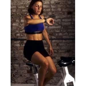  Young Woman Exercising on a Stationary Bike Checking her 